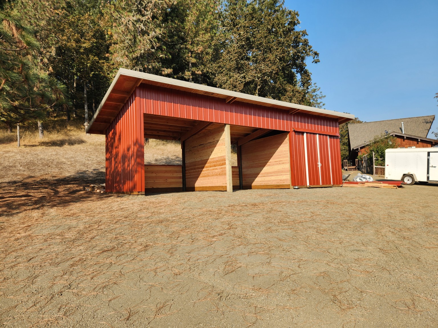Red post-frame livestock shelter with wood stall walls